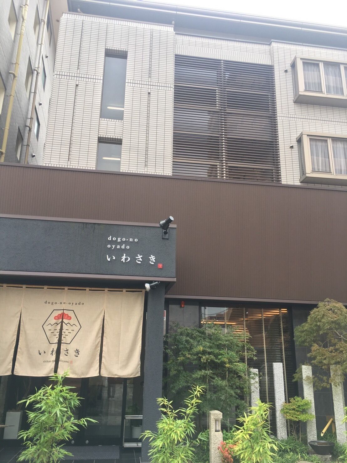 Un edificio con fachada moderna, que presenta un ventanal grande y un letrero con caracteres japoneses.