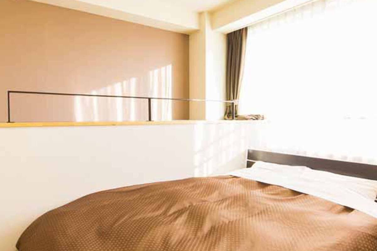 Un dormitorio con una cama, una ventana con cortinas y un estante en la pared.
