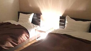 Un lit avec une tête de lit en bois, une literie blanche et une couverture marron.