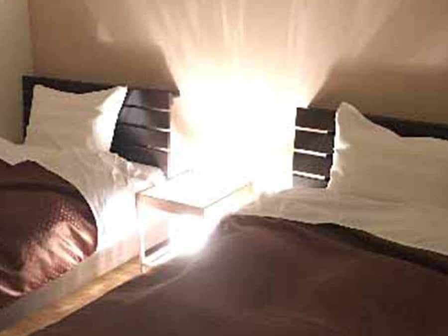 Ein Bett mit hölzernem Kopfteil, weißer Bettwäsche und einer braunen Decke.