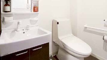 A bathroom with a white sink, mirror, and toilet.