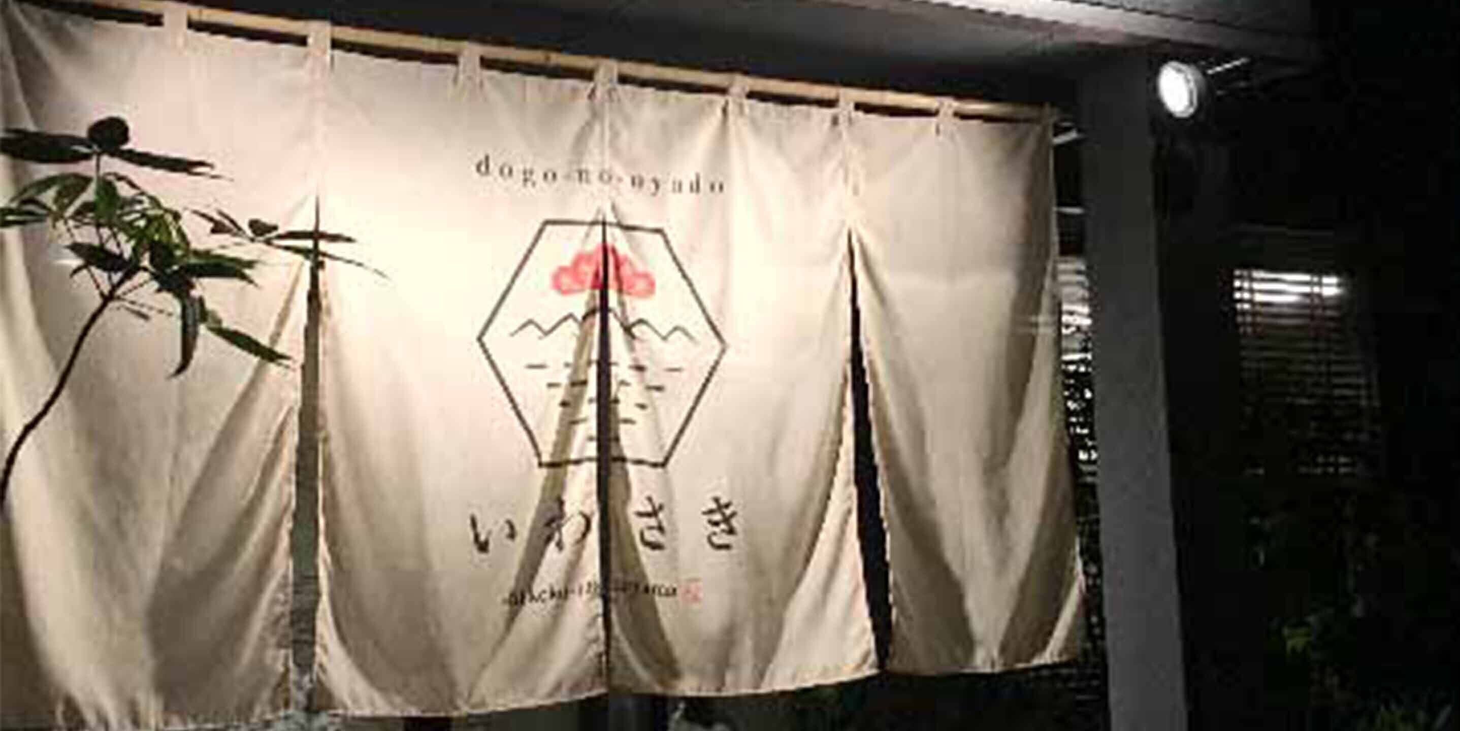 A banner with Japanese characters and a logo, hanging in a dimly lit room.