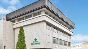 A modern hotel building with a flat roof, large windows, and a sign indicating it is the City Garden Hotel in Shinjuku. - Hotel Shinanoji (Nagano)