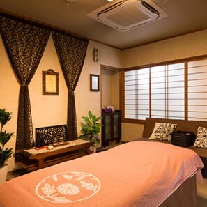 A room with a bed, a window with shoji screens, a small table, and a cabinet.