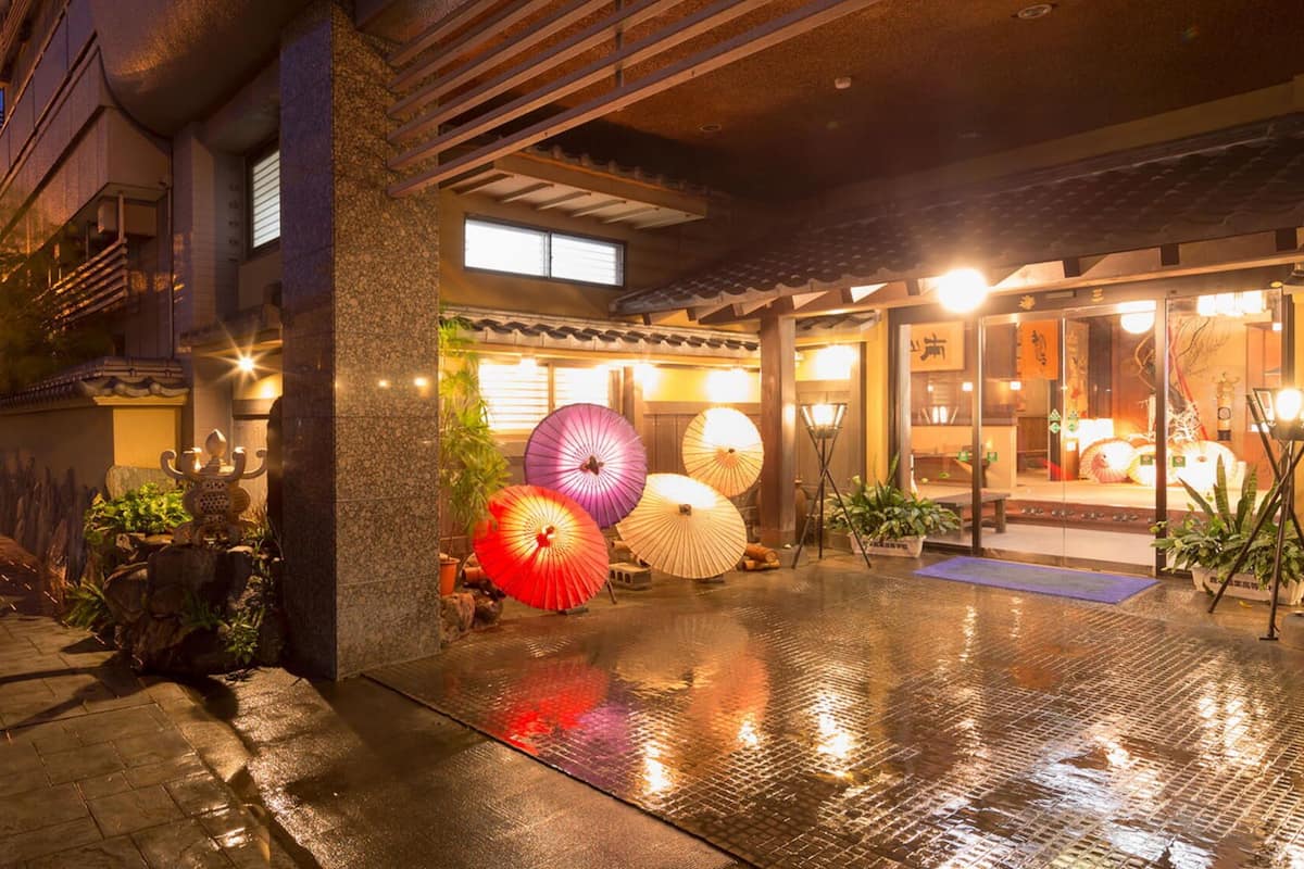 A traditional Japanese building with a wet ground, large umbrellas, and a visible entrance.