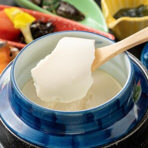 A bowl of white food with a wooden spoon.