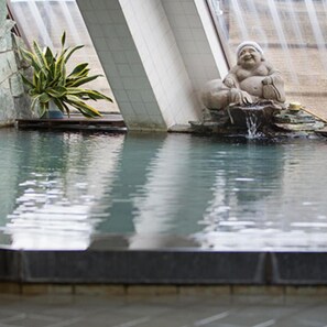 A stone statue of a seated figure by a small water feature. - Yamaga Onsen Sumi (Yamaga)