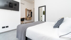A modern bedroom with a bed, a desk, and a mirror.