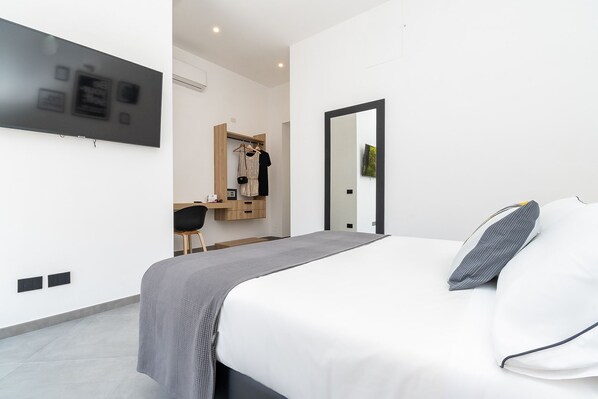 A modern bedroom with a bed, a desk, and a mirror.