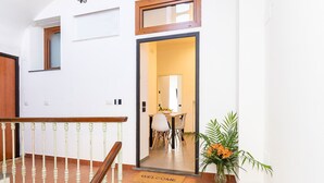 A staircase with a wooden handrail leading to a door with a 'WELCOME' mat.