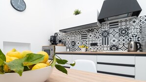 A modern kitchen with a black and white patterned backsplash, a coffee maker, and a kettle on the counter.