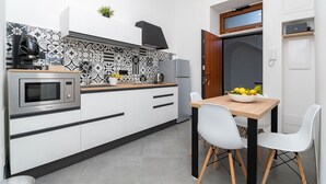 A compact kitchen with a microwave, refrigerator, and a small dining area with two chairs and a table.
