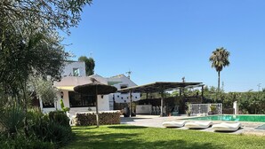 A well-maintained lawn, a swimming pool with lounge chairs, and a house with a patio area. - La ZÚA Rural Cottage in the Molino el Vado estate (Villamartin)