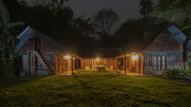 Een rustiek houten huis met een centrale patio, omgeven door weelderige begroeiing.