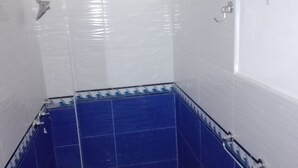 Ein kleines, separates Badezimmer mit weißen und blauen Fliesen, einer Dusche und einem WC.