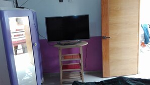 Ein Zimmer mit Fernseher auf einem kleinen Tisch, einem Kleiderschrank und einer violetten Wand.