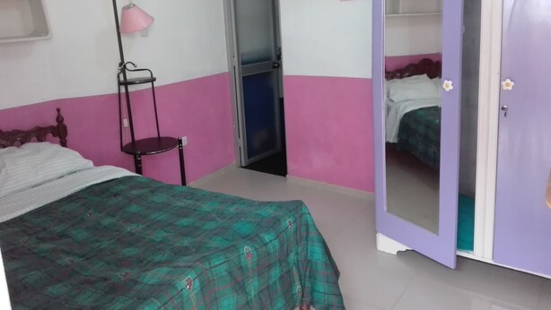 Ein Schlafzimmer mit Bett, Kleiderschrank, Stuhl und Schreibtischlampe.