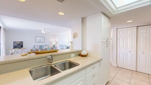 A modern kitchen with a double sink, a wooden tray, and a white cabinet.
