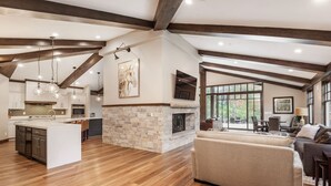 A spacious kitchen with a large island, stone fireplace, and wooden beams. - Mountain Lodge Overlooking Waterfall - Hot Tub, 5 bedroom, Unbelievable Views! (Sundance)
