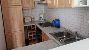 A compact kitchen with wooden cabinets, a stainless steel sink, and a coffee maker. - Apartment (W5) between forest and waves (Kellenhusen (Ostsee))