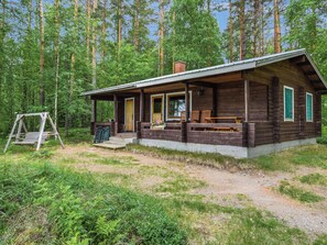 Une cabane rustique dotée d’un porche, d’une façade en bois et d’un chemin de terre menant à l’entrée.