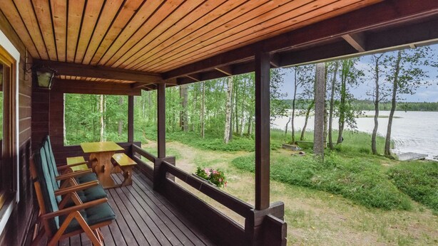 A wooden deck with benches and a table, overlooking a lake and forest. - Mäntyranta by Interhome (Savonlinna)