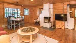 A cozy cabin interior with a dining area, a fireplace, a television, and a wooden ceiling. - Mäntyranta by Interhome (Savonlinna)