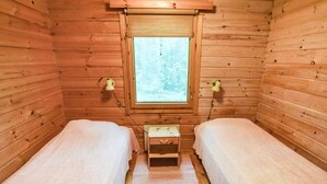 A cabin room with two beds, a window, and a small wooden chest. - Mäntyranta by Interhome (Savonlinna)