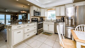 A modern kitchen with a central island, stainless steel appliances, and a view to the outside.
