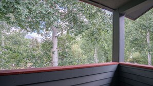 En hörna i ett rum med utsikt över träd genom ett fönster.