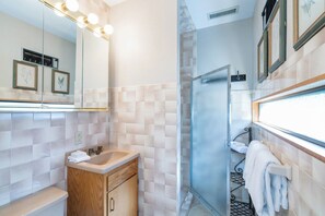 Une salle de bain équipée d’un miroir, d’un lavabo, d’un meuble-vasque et d’un espace douche.
