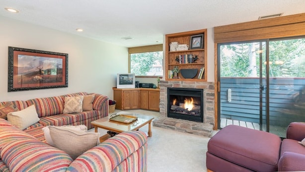 A living room with a fireplace, a sofa set, a television, and a bookshelf. - Telluride Lodge #532 2 Bedroom Condo (Telluride)