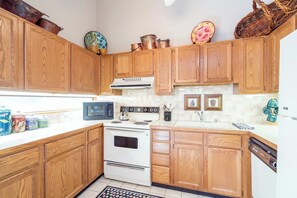 A kitchen with wooden cabinets, a white stove, a microwave, and a dishwasher.