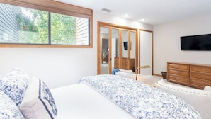 A bedroom with a large window, a bed with patterned bedding, a dresser, and a television mounted on the wall. - Telluride Lodge #532 2 Bedroom Condo (Telluride)