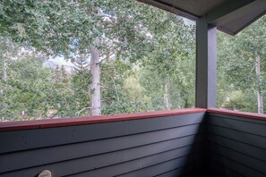 A corner of a room with a view of trees through a window.