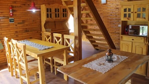 Un interior de madera con una mesa de comedor, sillas, una escalera y una zona de cocina.