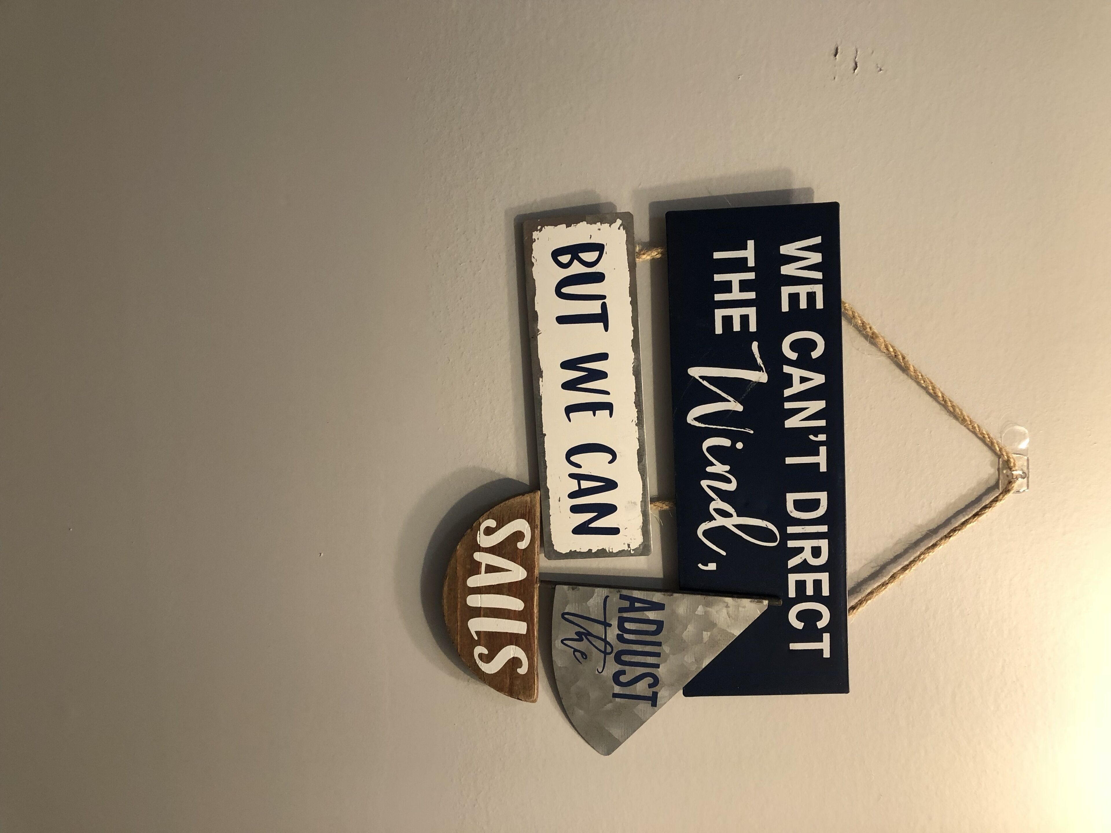 A wall with three signs: "We can't direct the wind," "But we can adjust sails," and "Sails."