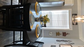 Un'area pranzo con un tavolo rotondo, sedie e un vaso con fiori.