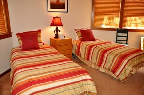 A room with two beds, a nightstand with a lamp, and a window with blinds. - Plunge D 2 Bedroom/ 2 Bathroom Downtown Condo (Telluride)