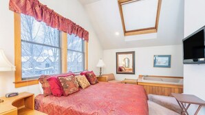 Une chambre à coucher avec un grand lit, une fenêtre donnant sur un beau paysage, un miroir, un lavabo et une télévision.