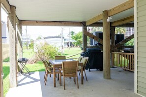 Eine überdachte Terrasse mit Tisch, Stühlen, einem Grill und Blick auf die Umgebung.