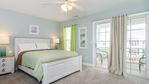 A bedroom with a bed, a nightstand, a ceiling fan, and a sliding glass door to a balcony. - Townhome 2 blocks from beach. Sleeps 10! (Carolina Beach)