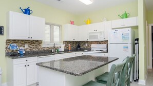 A kitchen with white cabinets, a granite countertop, and a central island. - Townhome 2 blocks from beach. Sleeps 10! (Carolina Beach)