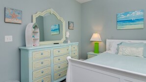 A bedroom with a bed, dresser, nightstand, and wall art. - Townhome 2 blocks from beach. Sleeps 10! (Carolina Beach)
