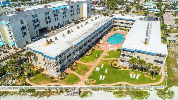 Un hôtel à plusieurs étages doté d’une piscine sur le toit, d’espaces extérieurs aménagés et d’une cour paysagée.
