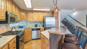 A kitchen with wooden cabinets, a stainless steel refrigerator, a dishwasher, and a gas stove. - Across from Lift 7 | 2BR + Loft | Hot Tubs, Fireplace, Walk to Town (Telluride)