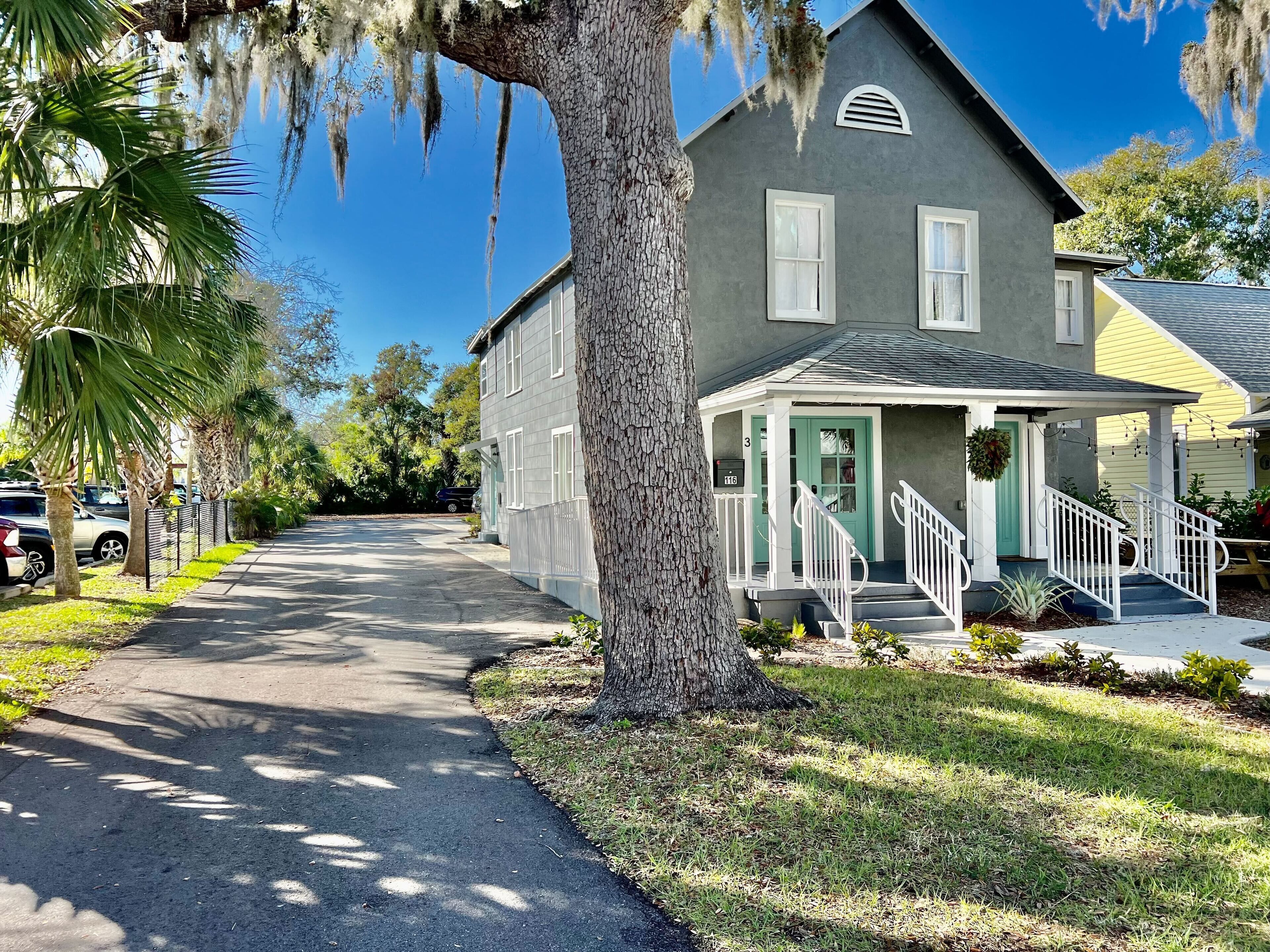 A residential street with a house featuring a porch, a mailbox, and a visible address number.