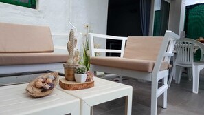 A white sofa with beige cushions, a white table with decorative items, and a white chair.