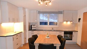Een moderne keuken met witte kasten, een houten eettafel en zwarte stoelen.
