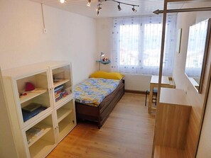 A bedroom with a bed, a desk, and built-in shelving. - Bennico by Interhome (Emmetten)